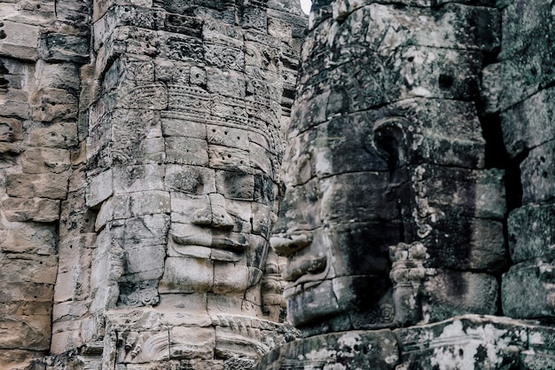 Oude steengezichten bij blauwe die hemel bewolkt van bayon-tempel, angkor wat, siam reap, kambodja.