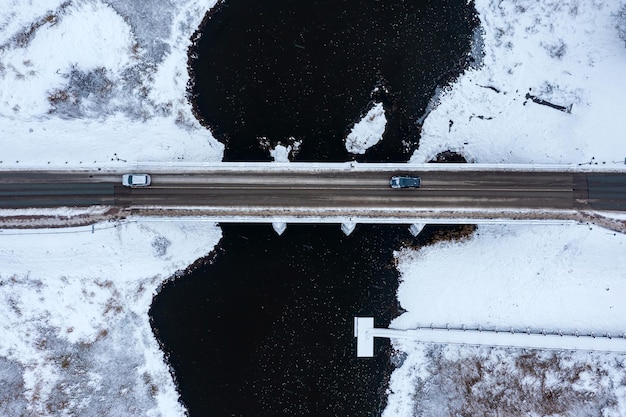 Oude stenen brug over de rivier op een besneeuwde winterdag van boven naar beneden