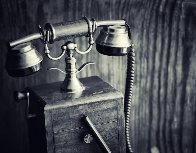 Oude telefoon en retro boek op het bureau. De telefoon van vroeger op een oud houten aanrecht. Lange afstand telefoongesprekken van de 19e eeuw.