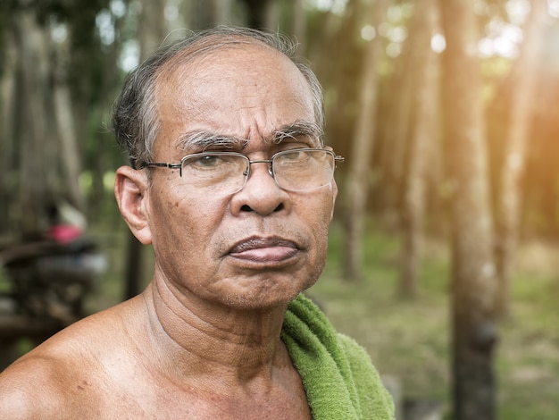 Oude Thaise tuinmanmens in rubberboomtuin