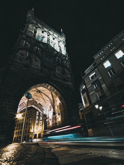 Foto oude toren in de stad 's nachts met passerende auto