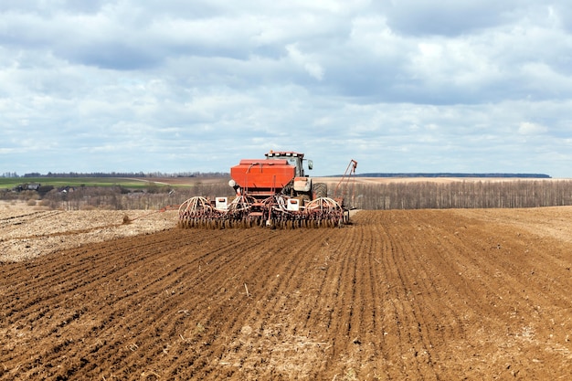 Oude tractor die tarwe in de lente opbrengt.