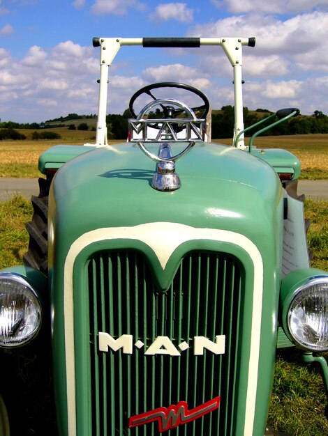 Foto oude tractor tegen bewolkte lucht