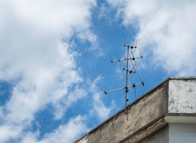 Oude tv-antenne geïnstalleerd op stedelijk huis. Afbeelding van het communicatieapparaat.