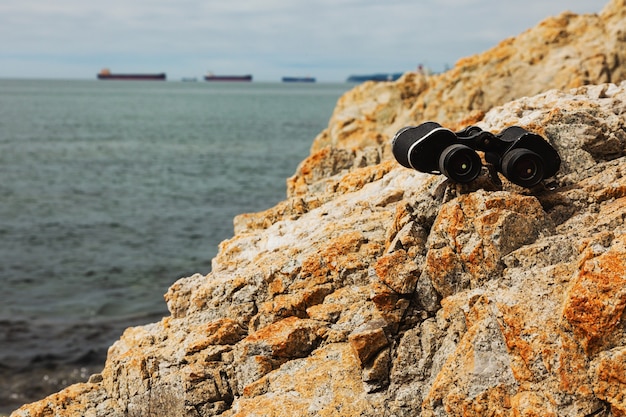 Oude verrekijker op de rotsen van de zeekust