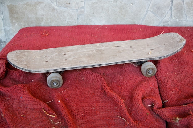 Oude vintage houten skateboard op een vuile rode ondergrond