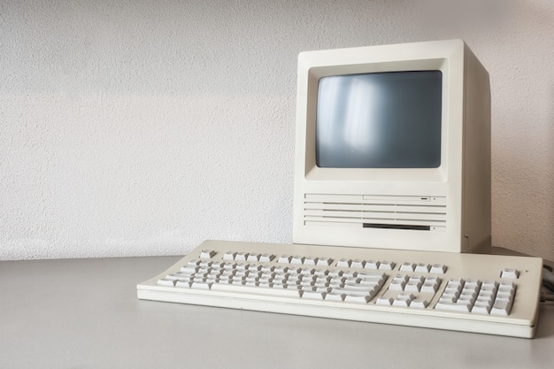 Oude vintage monitor en computer op bureau, retro werkplek met kopieerruimte, technologie,