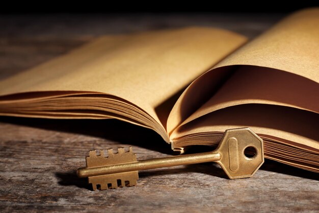 Oude vintage sleutel met boek op houten tafel