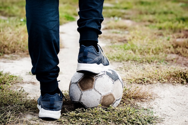 Oude voetbal met zijn voeten op het voetbalveld. Selectieve aandacht.