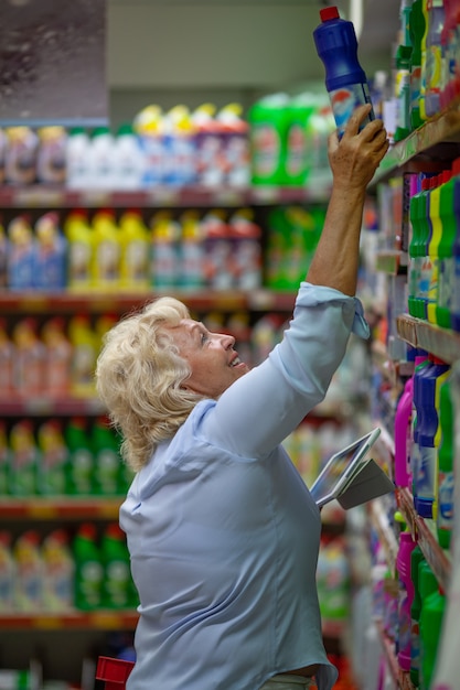 Oude vrouw die bij de supermarkt winkelt