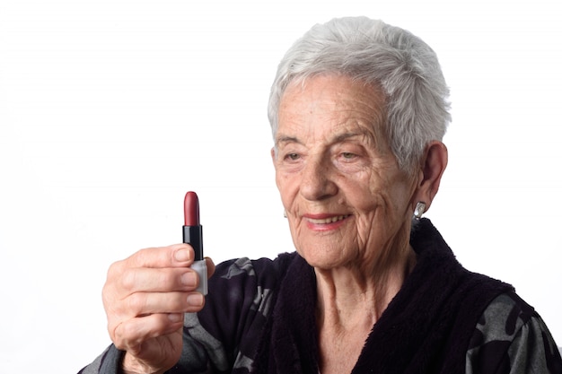 Oude vrouw die haar lippen op witte achtergrond schildert