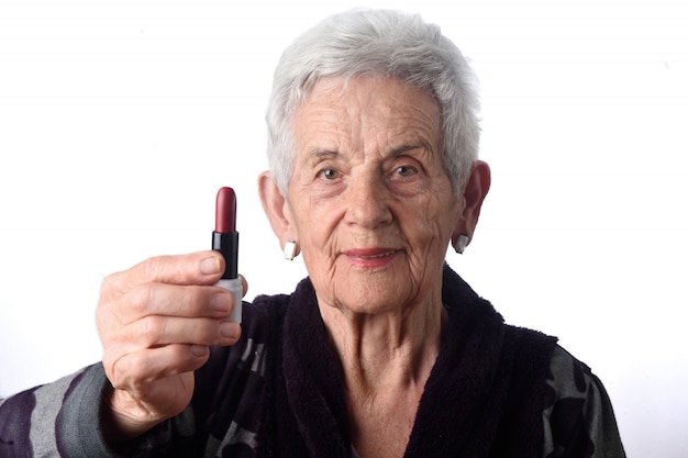 Oude vrouw die haar lippen op witte achtergrond schildert