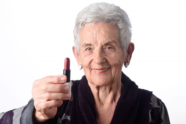 Oude vrouw die haar lippen op witte achtergrond schildert