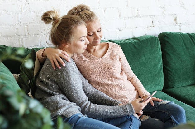 Oude vrouw en haar volwassen dochter die smartphone thuis gebruiken