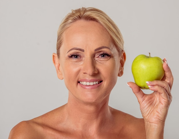 Oude vrouw met blote schouders met een appel.