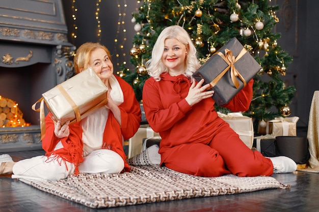 Oude vrouw met haar volwassen dochter die bij de kerstboom zit