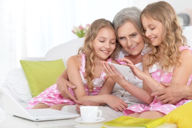 Oude vrouw met tweeniemeisjes en telefoon en laptop thuis