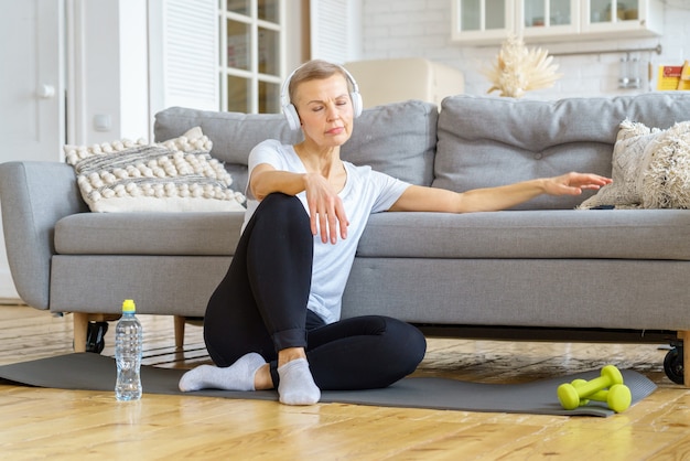 Oude vrouw ontspannen na fitnessactiviteit thuis luisteren naar muziek stressverlichtingsactiviteiten