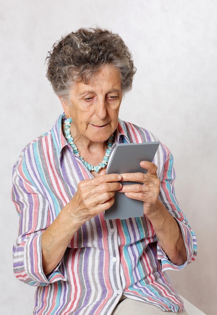 Oude vrouw tussen de 70 en 80 jaar controleert haar huid in de spiegel