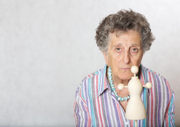 Foto oude vrouw tussen de 70 en 80 jaar oud met mini houten gemaakte etalagepop