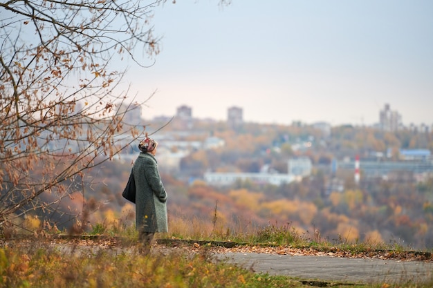 Oude vrouw wandelen in herfst stadspark