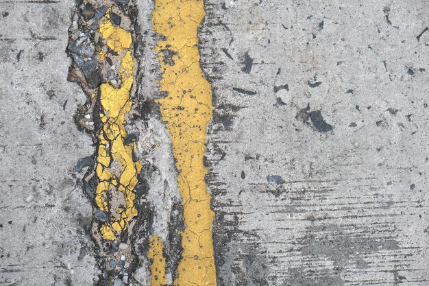 Oude wegachtergrond met gele lijnen die loskomen van veroudering