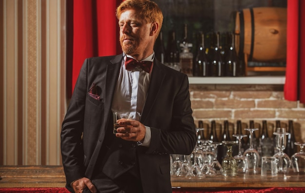 Oude whisky hipster die alcohol drinkt aan de bar, stijlvolle man in de pub