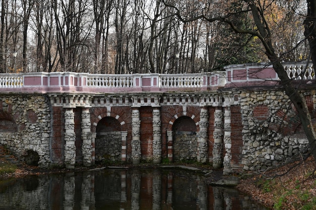 Oude witte stenen brug en grot. Panorama van het park. Vijver voor de grot.