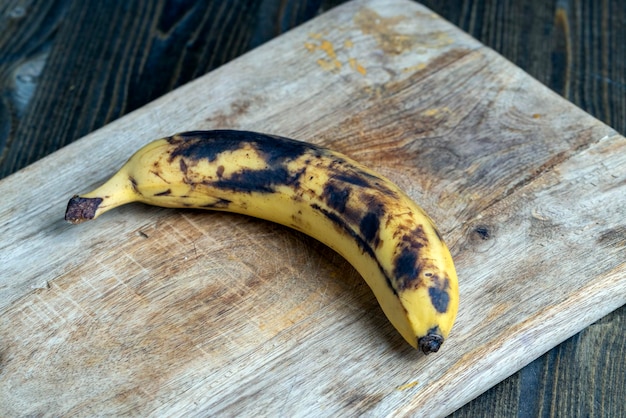 Oude zwart wordende banaan op een snijplank bederfelijke bananenfruitvoeding