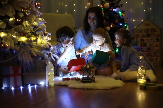 Oudejaarsavond Het huis is versierd voor de vakantie Netjes geklede kerstboom met een slinger en een gezin met cadeaus en een verrassing