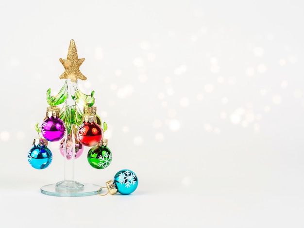 Oudejaarsavondfoto met een glazen kerstboom versierd met speelgoed op een witte achtergrond met bokeh Er is ruimte voor tekst