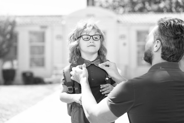 Ouder die kleine jongen verzamelt op de eerste klas om de vlinderdasschool te repareren