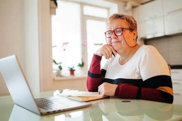 Ouder en wijzer een oudere vrouw met een bril gebruikt haar laptop om haar opleiding door middel van ele te bevorderen