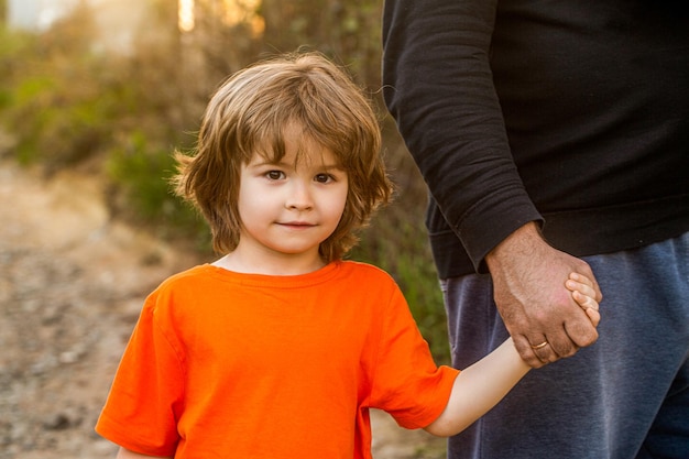 Ouder houdt de hand van een klein kind vast Vaders hand leidt zijn kind zoon vertrouwen familie concept Ouders houden de hand vast van een klein kind Kind hand vader Handen van ouder en kind buitenshuis