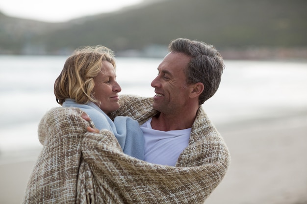 Ouder paar gewikkeld in een deken op het strand