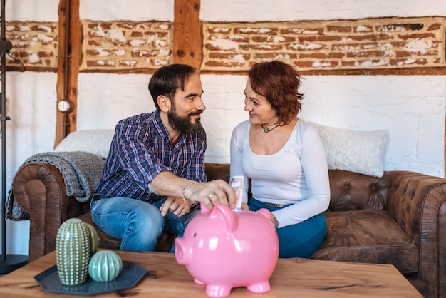 Ouder paar ontspannen thuis in de bank geld te besparen op het spaarvarken