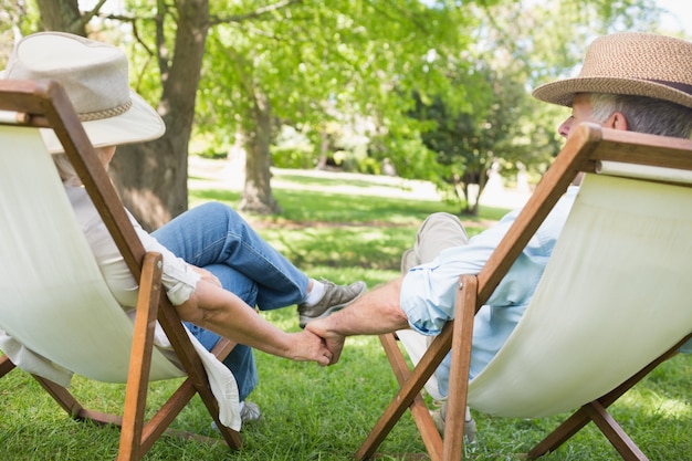 Ouder paar zitten in de ligstoelen op park