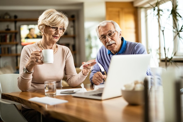 Ouder stel dat hun financiële rekening analyseert terwijl ze thuis via de computer betalen