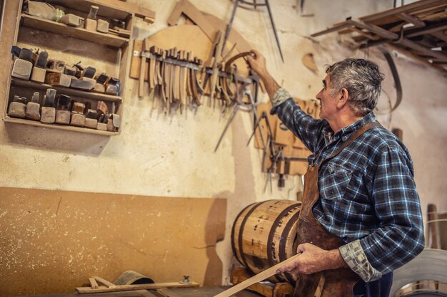 Oudere ambachtslieden plukken de benodigde onderdelen voor het maken van houten producten in een rustieke werkplaats.