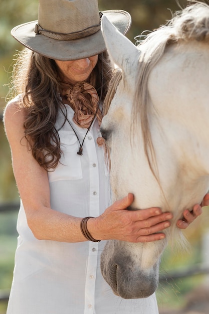 Oudere boerin met haar paard op de boerderij