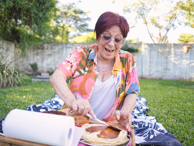 oudere dame bereidt pannenkoeken in het park met zoete melk