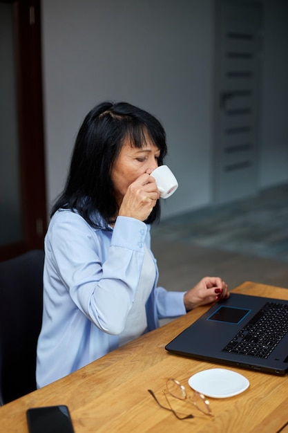 Oudere dame zakenvrouw ontspannen op de werkplek koffie drinken