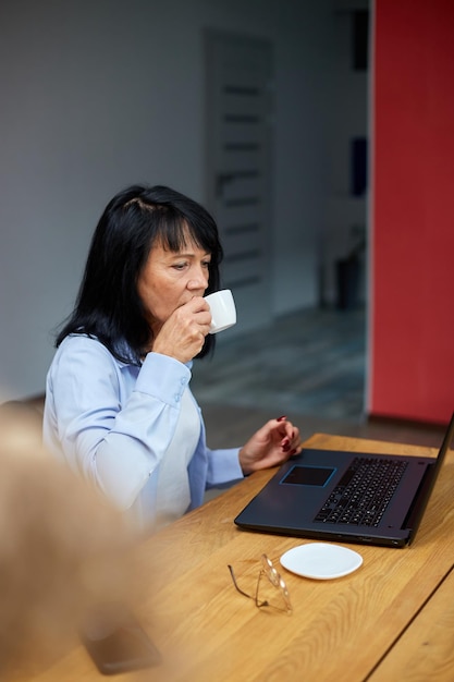 Oudere dame zakenvrouw ontspannen op de werkplek koffie drinken