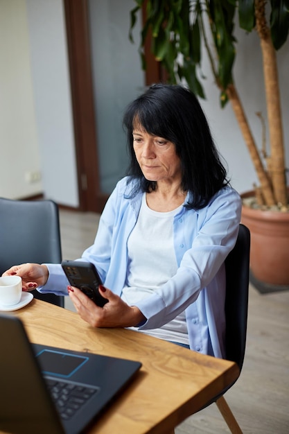 Oudere dame zakenvrouw ontspannen op de werkplek met behulp van mobiele telefoon