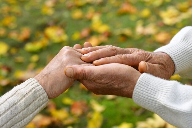 Oudere echtpaar die elkaar de handen vasthouden in het herfstpark