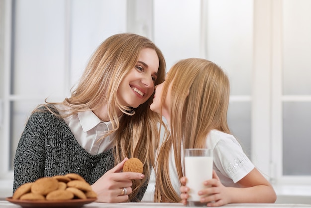 Oudere en jongere zussen die koekjes eten.