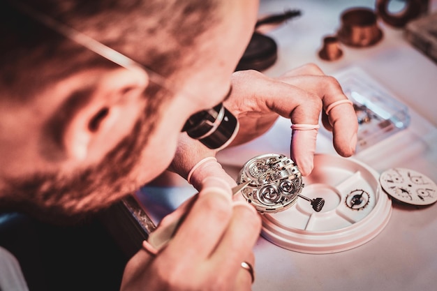 Foto oudere klokkenmeester repareert een oud horloge voor een klant in zijn drukke reparatiewerkplaats.