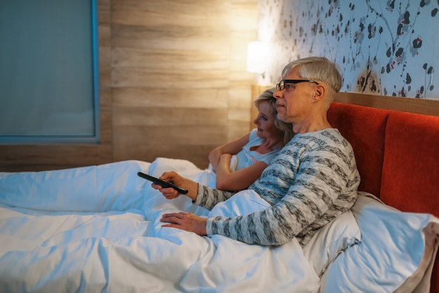 Oudere liefde paar tv kijken in de slaapkamer