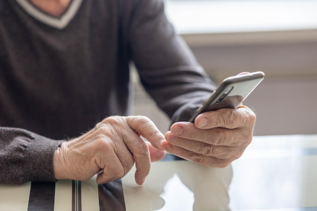 Oudere man belt nummer in smartphone vanuit huis