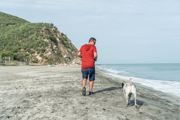 Oudere man die 's ochtends plezier heeft met zijn hond op het strand